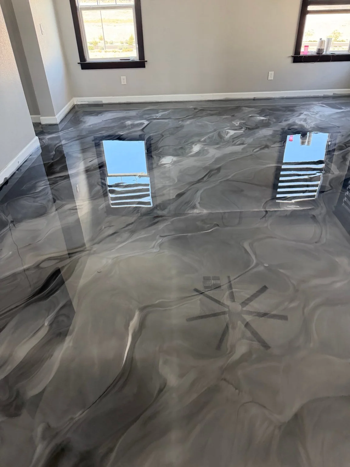 Finished gray and charcoal floor by Resinart Finishes, showing flowing patterns and window reflections